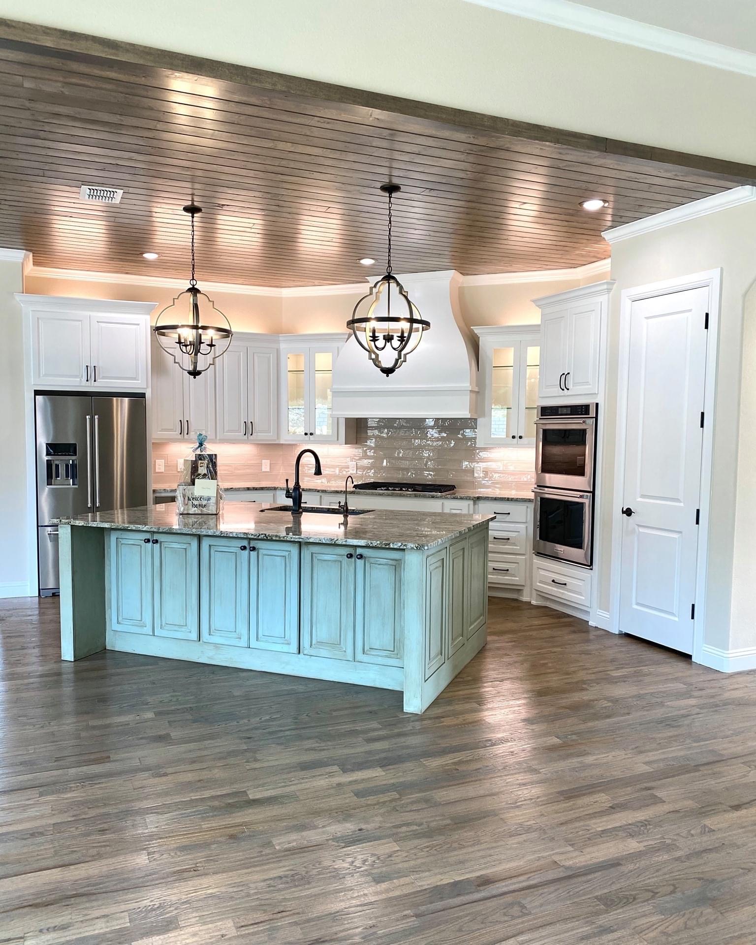 Farmhouse kitchen with white cabinetry and a weathered blue-green island